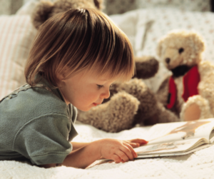 Image of a child reading a book with teddy bears in the background