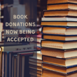 A photograph of a stack of books with text that reads "book donations now being accepted"