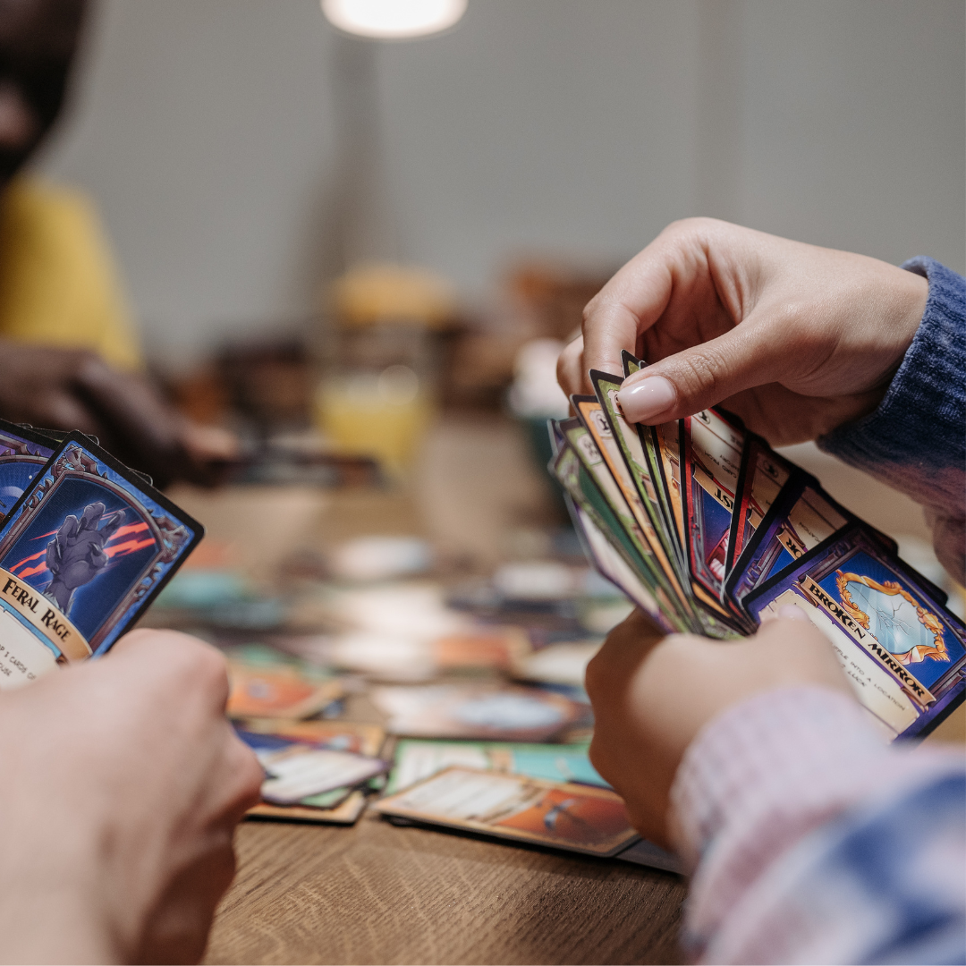 A closeup photograph of people playing a card game around a table.